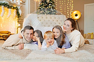 Beautiful happy large family on the floor in room with the Christmas tree.