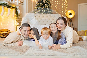 Beautiful happy large family on the floor in room with the Christmas tree.