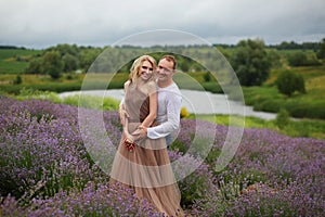 beautiful and happy laughing couple hugging in lavender field, blonde girl