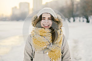 Beautiful happy laughing young woman wearing winter hat and scarf. winter background with snow. Winter holidays concept