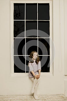 Beautiful happy Lille girl sitting near big window