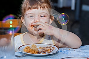 Beautiful happy little girl biting birthday cake