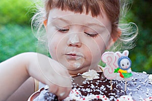 Beautiful happy little girl biting birthday cake