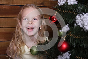 Beautiful happy little girl laughing near the Christmas tree.