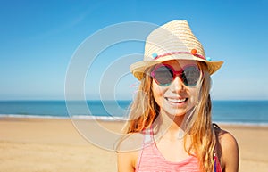 Beautiful happy little girl in straw hat on beach