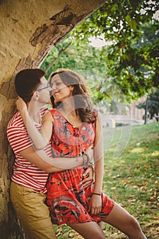 Beautiful happy loving couple on nature near to big tree embracing and looking at each other. A moment before a kiss