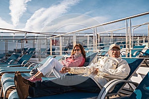 beautiful happy middle aged couple relaxing on deck chairs of a cruise ship