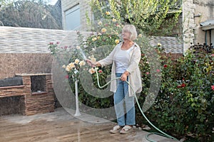 Beautiful happy middle aged woman caring for the summer garden.