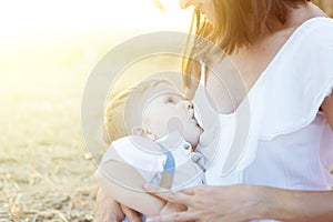 Beautiful happy mother breastfeeding her baby boy outdoor