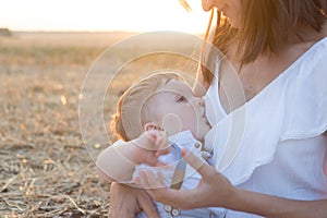 Beautiful happy mother breastfeeding her baby boy outdoor.