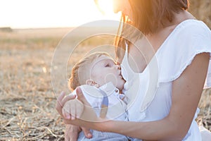 Beautiful happy mother breastfeeding her baby boy outdoor.