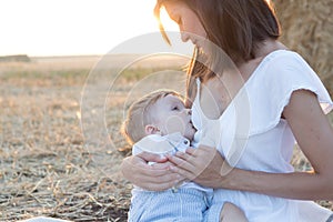 Beautiful happy mother breastfeeding her baby boy outdoor.