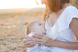 Beautiful happy mother breastfeeding her baby boy outdoor.