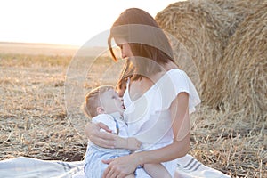 Beautiful happy mother breastfeeding her baby boy outdoor.