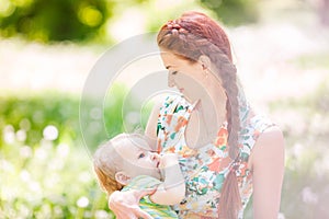 Beautiful happy mother breastfeeding outdoor