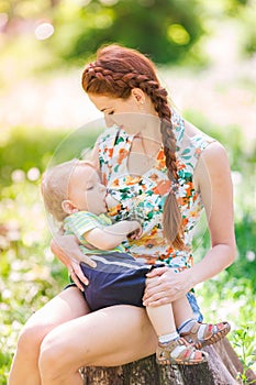 Beautiful happy mother breastfeeding outdoor