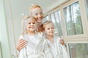 beautiful happy mother and children in bathrobes smiling