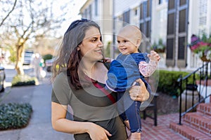 Beautiful happy mother holding her cute baby in peaceful neighborhood