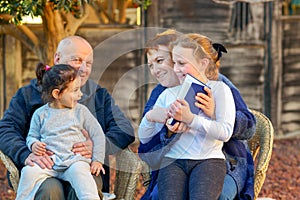 Beautiful Happy Old couple and granddaughters reading a book together in the nature at sunset.