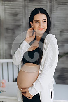 Beautiful happy pregnant african woman hugging her tummy, sitting on sport mat, enjoying her pregnancy, free space