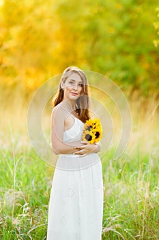 Beautiful happy pregnant girl on the field of daisy flowers in sunset lights