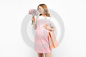 Beautiful happy pregnant woman with shopping bags touching her big belly on white background