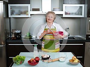 Beautiful and happy senior woman cooking at her kitchen