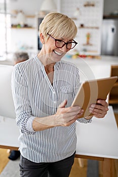 Beautiful happy senior woman using tablet computer at home