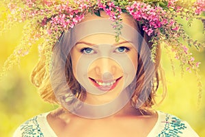 Beautiful happy Slavic girl in a wreath of summer flowers