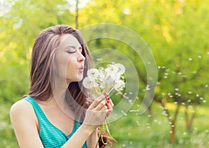 Beautiful happy smiling girl with long dandelions in the hands of shorts and a t-shirt is resting in the Park on a Sunny day