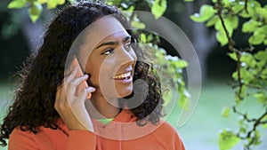 Beautiful, happy, smiling mixed race African American girl teenager young woman outdoors talking on her smartphone or cell phone