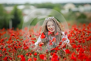 Beautiful happy smiling teen girl portrait with red flowers on head enjoying in poppies field nature background. Makeup