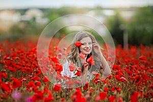 Beautiful happy smiling teen girl portrait with red flowers on head enjoying in poppies field nature background. Makeup