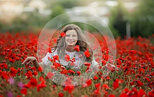 Beautiful happy smiling teen girl portrait with red flowers on head enjoying in poppies field nature background. Makeup