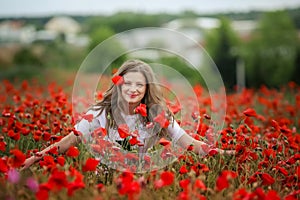 Beautiful happy smiling teen girl portrait with red flowers on head enjoying in poppies field nature background. Makeup