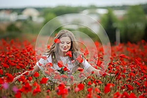 Beautiful happy smiling teen girl portrait with red flowers on head enjoying in poppies field nature background. Makeup