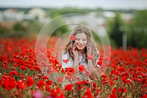 Beautiful happy smiling teen girl portrait with red flowers on head enjoying in poppies field nature background. Makeup