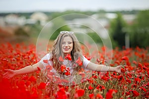 Beautiful happy smiling teen girl portrait with red flowers on head enjoying in poppies field nature background. Makeup