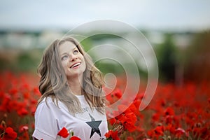 Beautiful happy smiling teen girl portrait with red flowers on head enjoying in poppies field nature background. Makeup