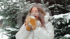 Beautiful happy smiling winter woman in warm clothes drinking coffee from disposable paper cup while walking in