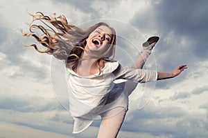 Beautiful happy smiling woman with hair flying in the sky background