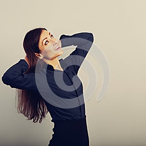 Beautiful happy smiling woman with long brown healthy hair style holding arms behind the head and looking up in blue shirt, formal