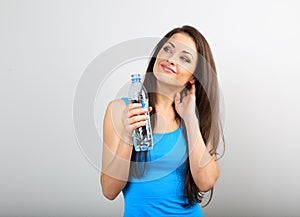 Beautiful happy sporty slim woman holding bottle with water and with thinking how to lose weight on blue background