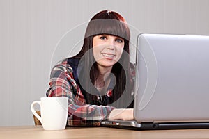 Beautiful happy student doing homework on laptop