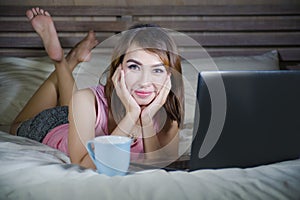 Beautiful and happy student woman enjoying on bed with laptop co