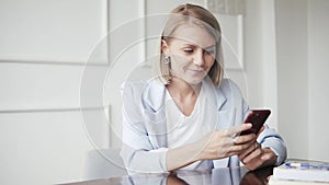 Beautiful and happy, successful business woman with mobile phone and notepad in a cafe, working as a freelancer. Blonde