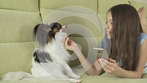 Beautiful happy teenage girl communicating in smartphone and with her dog