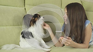 Beautiful happy teenage girl communicating in smartphone and with her dog