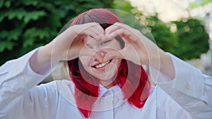 Beautiful happy teenage girl showing heart sign with hands, outdoor in the city