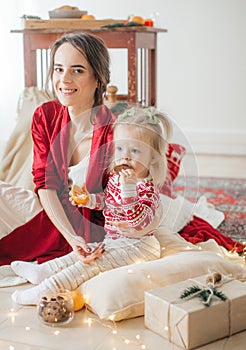 Beautiful happy woman with baby girl near a Christmas tree with gifts